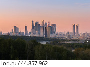 Башни-высотки района "Москва-Сити" в вечернее время с Воробьёвых гор. Красочное оранжево-голубое летнее небо. Изгиб Москвы-реки с проплывающим теплоходом. Редакционное фото, фотограф Сергей Никифоров-Гордеев / Фотобанк Лори