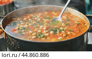 Chef adds spices to a large pot of soup, stirring it with a spoon. Стоковое AI-видео, аниматор Юрий Поздников / Фотобанк Лори