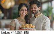 Young indian couple smiles while holding a plate of food. Стоковое AI-видео, аниматор Юрий Поздников / Фотобанк Лори