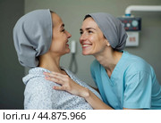 A breast cancer survivor shares a joyful moment with a healthcare professional, both smiling and displaying warmth in a treatment room. Their connection highlights hope and resilience. Generative AI. Стоковое AI-изображение, AI-художник Юлия Петровская / Фотобанк Лори