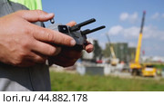 a surveyor on a construction site controls a quadcopter. Стоковое видео, видеограф Igor Skripachev / Фотобанк Лори