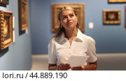 Woman with sheet piece of paper in hands view pictures and icons in museum hall. Стоковое видео, видеограф Яков Филимонов / Фотобанк Лори