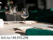 Stylish table setting. Glass glasses, plates, cutlery on the table. Wedding service, reception at the dining table. A birthday, a baptism, a festive event. Стоковое фото, фотограф Photojuli / Фотобанк Лори