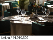 Stylish table setting. Glass glasses, plates, cutlery on the table. Wedding service, reception at the dining table. A birthday, a baptism, a festive event. Стоковое фото, фотограф Photojuli / Фотобанк Лори