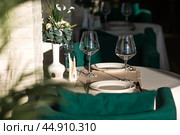 Stylish table setting. Glass glasses, plates, cutlery on the table. Wedding service, reception at the dining table. A birthday, a baptism, a festive event. Стоковое фото, фотограф Photojuli / Фотобанк Лори