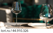 Stylish table setting. Glass glasses, plates, cutlery on the table. Wedding service, reception at the dining table. A birthday, a baptism, a festive event. Стоковое фото, фотограф Photojuli / Фотобанк Лори