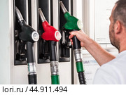 Gas station. Refueling the car with gasoline. A man holds a Russian fuel dispenser at a gas station. Rising fuel prices around the world. Стоковое фото, фотограф Photojuli / Фотобанк Лори