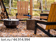 Eco-friendly, stylish barbecue area and wooden chairs for relaxing by the campfire. An axe will be stuck into a wooden log. Chopping firewood. Стоковое фото, фотограф Photojuli / Фотобанк Лори