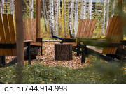 Eco-friendly, stylish barbecue area and wooden chairs for relaxing by the campfire. An axe will be stuck into a wooden log. Chopping firewood. Стоковое фото, фотограф Photojuli / Фотобанк Лори