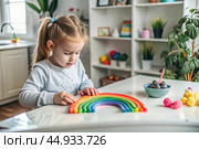 Toys. A little girl is playing educational games. A rainbow-shaped children's toy, colored pyramids and logic toys for children. Montessori games for child development. Стоковое AI-изображение, AI-художник Photojuli / Фотобанк Лори