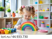 Toys. A little girl is playing educational games. A rainbow-shaped children's toy, colored pyramids and logic toys for children. Montessori games for child development. Стоковое AI-изображение, AI-художник Photojuli / Фотобанк Лори