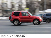 Side view of Mitsubishi Pajero 3-door SUV. Fast moving car on the street. Red vehicle driving along the street in city with blurred background. Редакционное фото, фотограф Константин Григорьев / Фотобанк Лори