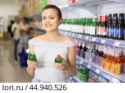 Asian female shopper choosing alcoholic beverage at liquor store. Стоковое фото, фотограф Яков Филимонов / Фотобанк Лори