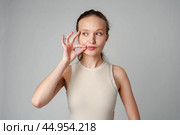 Young Woman Making a Hush Gesture on gray background in studio. Стоковое фото, фотограф Сергей Толмачёв / Фотобанк Лори