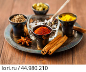 Oriental spice set - coriander, red pepper, turmeric, cinnamon, star anise, rosemary various seasonings in metall cups, on brown wooden table, side view, mcro, selective focus. Стоковое фото, фотограф Natalia Gdovskaia / Фотобанк Лори