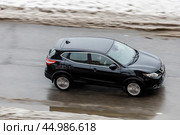 Aerial side view of Nissan Qashqai suv in motion. Black CUV car moving on the slippery winter street. Редакционное фото, фотограф Константин Григорьев / Фотобанк Лори