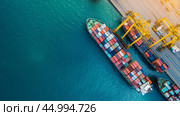 Cargo ships docked at a shipping port unloading containers during sunset near tranquil blue waters. Стоковое AI-изображение, AI-художник Сергей Толмачёв / Фотобанк Лори