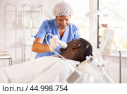 Aesthetician administering facial procedure using ice hammer on dark-skinned man. Стоковое фото, фотограф Яков Филимонов / Фотобанк Лори