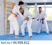Senior man, karate sensei, engaging kumite with young guy in training room. Стоковое фото, фотограф Яков Филимонов / Фотобанк Лори