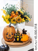 A vase of flowers, pumpkins and a scary castle with a witch on the background of a Scandi-style white kitchen interior. The concept of home and comfort. Autumn decor for Halloween. Стоковое фото, фотограф Photojuli / Фотобанк Лори