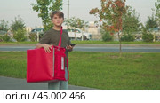 Child is compelled to work as a delivery courier, searching for a designated address in the urban environment to which he must deliver the goods. Стоковое видео, видеограф Strunov David / Фотобанк Лори