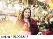 Happy girl with paper cup of coffee walking in Christmas fair. Стоковое фото, фотограф Яков Филимонов / Фотобанк Лори