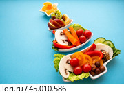 Plate in the form of a Christmas tree with vegetables, fruits, mushrooms and berries. Blue background. The concept of vegetarian holiday food. Стоковое фото, фотограф Юлия Ильина / Фотобанк Лори