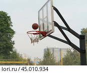Photography of sports competitions on the sports ground in the Gorky park. Basketball basket and ball falling into it in summer day. Healthy lifestyles of youth. Стоковое фото, фотограф YuryKara / Фотобанк Лори
