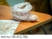 Solitary plastic bag containing fish entrails rests on a stark table, evoking themes of waste, consumption, and the overlooked remnants of everyday choices within a consumer society. Стоковое фото, фотограф Татьяна Степанищева / Фотобанк Лори