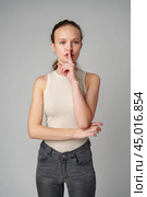 Young Woman Making a Hush Gesture on gray background in studio. Стоковое фото, фотограф Сергей Толмачёв / Фотобанк Лори