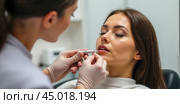 Beautician performing lip injection procedure on young woman in aesthetic clinic. Close-up of beauty treatment for enhancing lips. Cosmetic procedure for fuller lips. Стоковое AI-изображение, AI-художник Павел Муравьев / Фотобанк Лори