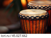 Two wooden djambe drums standing side by side waiting to be played. Стоковое AI-изображение, AI-художник Иван Рябоконь / Фотобанк Лори