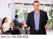 Dispassionate secretary man stands at reception with folder and list of guests and expects visitors. Стоковое фото, фотограф Яков Филимонов / Фотобанк Лори