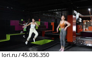 Enthusiastic middle-aged woman experiencing thrill of leaping high at vibrant trampoline gym with friends. Стоковое видео, видеограф Яков Филимонов / Фотобанк Лори