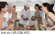 Elderly woman holds glass of cool white wine in hands and converse with participant at culinary courses. Стоковое видео, видеограф Яков Филимонов / Фотобанк Лори