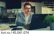 Professional man working intently at a laptop in a contemporary office setting during the day. Стоковое видео, видеограф Сергей Толмачёв / Фотобанк Лори