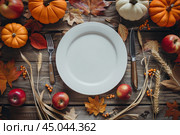 White plate on autumn background. Rustic menu mockup fall table setting decoration, colorful leaves. Floral interior decor for holidays with pumpkins. Thanksgiving dinner concept. Flatlay, top view. Стоковое AI-изображение, AI-художник Марина Демидюк / Фотобанк Лори