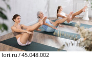 Three generation of women perform sitting boat pose Paripurna Navasana. Стоковое фото, фотограф Яков Филимонов / Фотобанк Лори