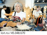 Old woman choosing second hand clothes in large clothing shop. Стоковое фото, фотограф Яков Филимонов / Фотобанк Лори
