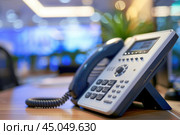 Modern voip phone standing on office desk in modern office interior. Стоковое AI-изображение, AI-художник Иван Рябоконь / Фотобанк Лори