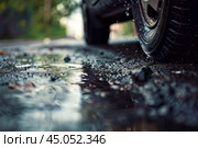 Car tire driving through puddle on wet asphalt road. Стоковое AI-изображение, AI-художник Иван Рябоконь / Фотобанк Лори