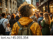 Portrait of a curly-haired mulatto traveler in a yellow jacket and with a backpack in the city. Traveling alone is a lifestyle. A young tourist is enjoying his autumn vacation. Стоковое AI-изображение, AI-художник Photojuli / Фотобанк Лори