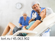Male doctor with nurse help gives injection of botulinum toxin to client in lip area. Стоковое фото, фотограф Яков Филимонов / Фотобанк Лори