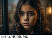 A teenage girl with a sad face alone by the window. It's raining outside the window. The concept of loneliness, depression, melancholy, resentment and bad mood. Стоковое AI-изображение, AI-художник Photojuli / Фотобанк Лори