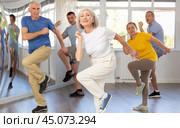 Elderly woman practicing Tai Chi with group in training room. Стоковое фото, фотограф Яков Филимонов / Фотобанк Лори