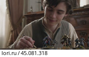 Young man painting fantasy miniatures at home. Стоковое AI-видео, аниматор Юрий Поздников / Фотобанк Лори