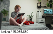 A girl with glasses is surfing the Internet at home in a cozy atmosphere and uses a tablet and a stylus. The glasses reflect the pages you scroll through on the Internet. Стоковое видео, видеограф Енваев Андрей / Фотобанк Лори