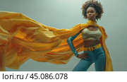 African-American young woman dressed in superhero costume with flowing yellow cape on grey background, looking at the camera, copyspace,, concept of fashion design, creative industry. Стоковое AI-видео, аниматор Ирина Михайличенко / Фотобанк Лори
