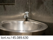 Sleek metal sink and faucet in a public restroom, embodying functionality and minimalism. The polished surface reflects a modern design ethos, ensuring cleanliness and efficiency. Стоковое фото, фотограф Татьяна Степанищева / Фотобанк Лори
