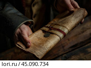 Historian holding old scroll with wax seal and ribbon. Стоковое AI-изображение, AI-художник Иван Рябоконь / Фотобанк Лори